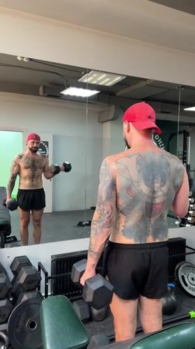 Dumbbell curls in a Voronezh gym, mirror reflection in frame.