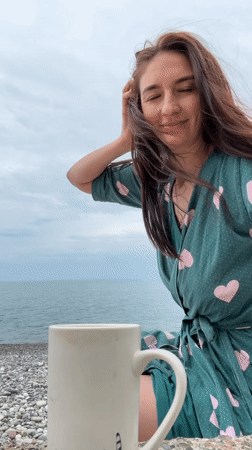 Woman in heart-patterned robe enjoys morning beach moment in Sochi