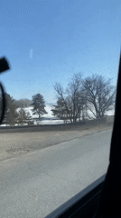 Vehicle travels snow-covered road beside frozen water in Russia