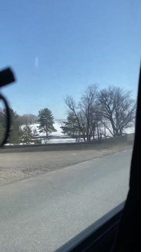 Vehicle travels snow-covered road beside frozen water in Russia