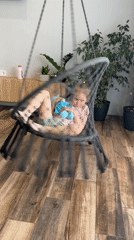 Child relaxes in hanging chair with stuffed animal, Chaikovsky