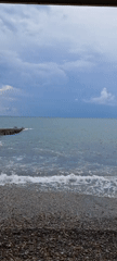 Sochi's pebble beach and pier on a cloudy summer afternoon