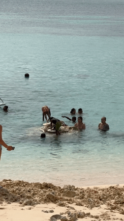 Woman photographs swimmers in turquoise waters at General Luna beach