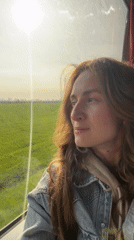 Woman gazes from window at sunny morning in Kamianets