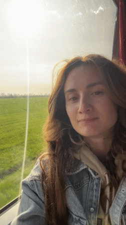 Woman gazes from window at sunny morning in Kamianets