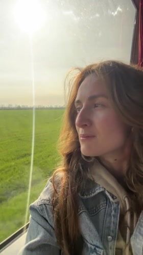 Woman gazes from window at sunny morning in Kamianets