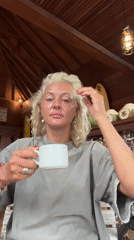 Woman drinks from mug in wooden-beamed interior