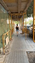 Woman walks past construction scaffolding in sunny Castelló