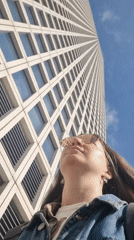 Woman observes tall white building in Tel Aviv