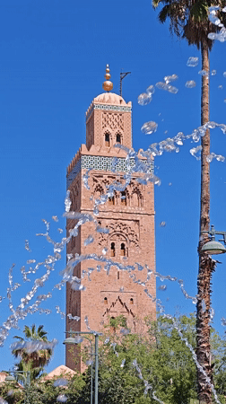 Pink mosque tower filmed through fountain in Marrakesh