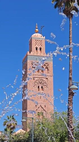 Pink mosque tower filmed through fountain in Marrakesh