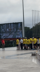 Group watches factory production footage on outdoor screen in Da Lat
