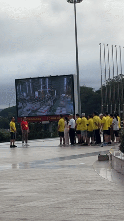 Group watches factory production footage on outdoor screen in Da Lat
