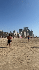 Beachgoers play volleyball on sunny Tel Aviv beach