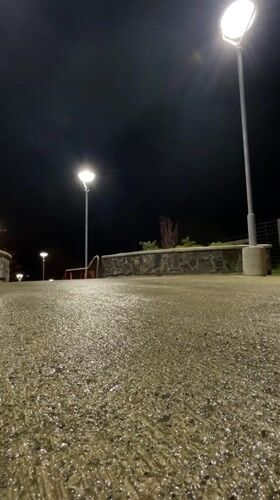Two people walk wet Ushuaia walkway at night