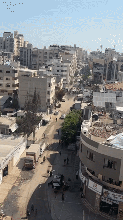 Crowds move through damaged Gaza streets amid building collapses