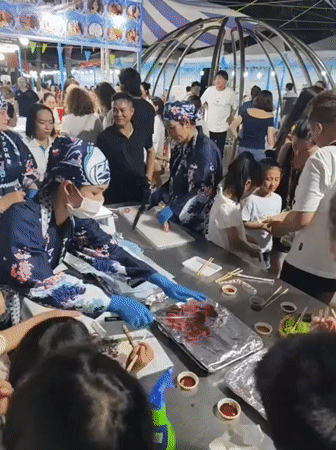 Busy night street scene: food stall, red rabbit mascot, crowd, police