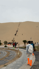 Tourists climb sand dunes in Dunhuang, China