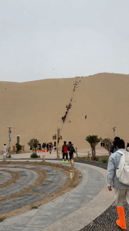 Tourists climb sand dunes in Dunhuang, China