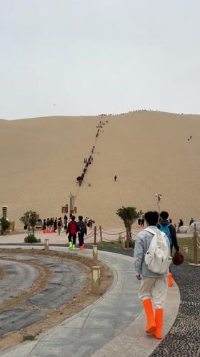 Tourists climb sand dunes in Dunhuang, China