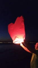 Evening sparklers and sky lanterns on Greek beach at sunset