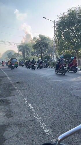 Busy road traffic through Candi with smoke visible in distance