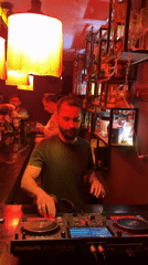 DJ operates mixing equipment behind bar with staff present