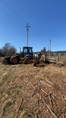 Backhoe loader operates in field near Putrishki, Belarus