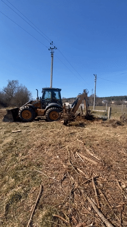 Backhoe loader operates in field near Putrishki, Belarus