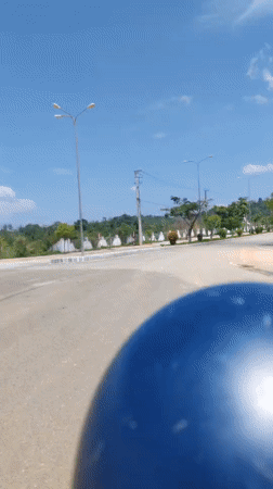 Helmet-wearing rider travels paved road in Bo Y, Vietnam