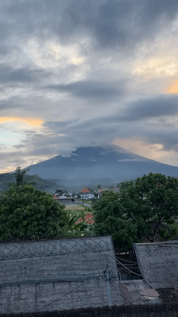 Mount Agung emerges through morning clouds over Bali countryside