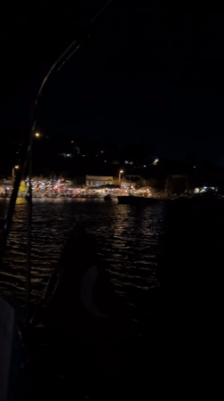 Festive harbor night: sailboats, moonlight, and lit-up waterfront
