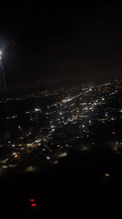 Passenger films nighttime city lights from airplane over Kuta