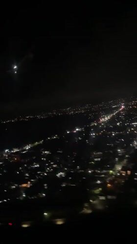 Passenger films nighttime city lights from airplane over Kuta