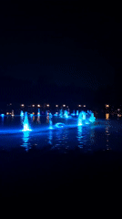 Nighttime water fountains display blue-green light show