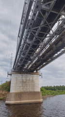 River traffic moves past a steel railway bridge in Tarkanovo