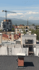 Construction workers paint rooftop in Plovdiv, Bulgaria
