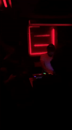Late-night DJ set observed in red-lit Tel Aviv venue