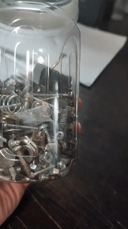 Jar of mixed metal hardware held up for a look