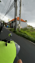 Motorbike rider travels paved road in overcast Dalung morning