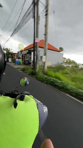 Motorbike rider travels paved road in overcast Dalung morning