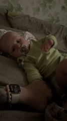 Baby in green onesie, quiet moment at home