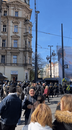 Large crowd gathers with police presence in Prague street