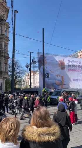 Large crowd gathers with police presence in Prague street