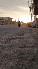 Sunset traffic moves through a dusty roadside stretch in Meunasah Raya
