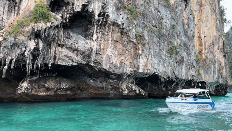 Speedboat passes dramatic limestone cliffs in Ao Nang