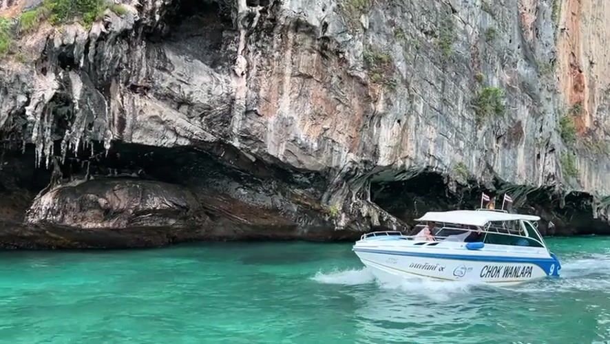Speedboat passes dramatic limestone cliffs in Ao Nang