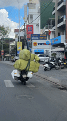 Loaded motorcycle carries wrapped packages through Đà Lạt streets