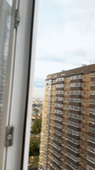 Woman watches rainbow from apartment window in Ovoshchnoy, Russia