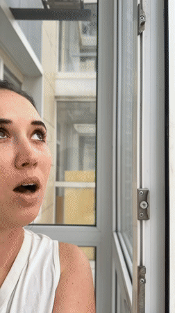 Woman watches rainbow from apartment window in Ovoshchnoy, Russia